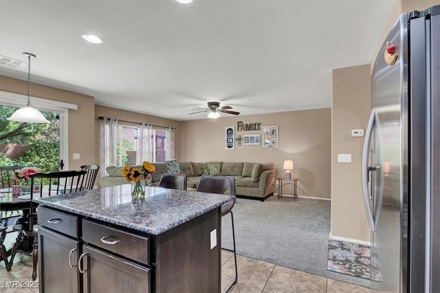 10230 Danskin Dr, Las Vegas, NV 89166 - kitchen featuring freestanding refrigerator, light colored carpet, a breakfast bar, dark brown cabinets, and light tile patterned floors