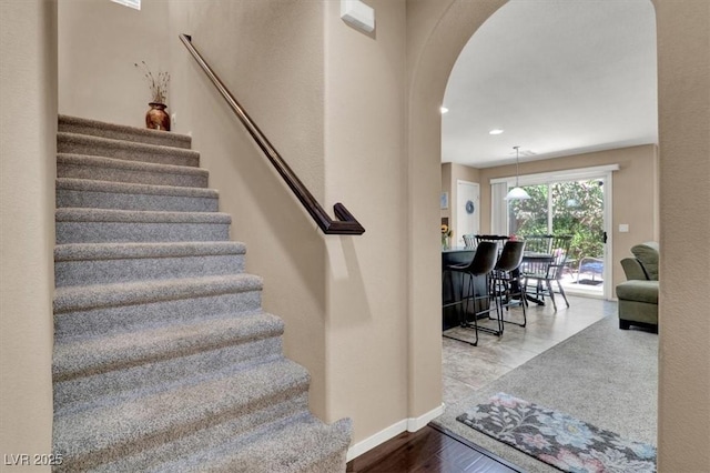 10230 Danskin Dr, Las Vegas, NV 89166 - staircase with arched walkways, baseboards, and wood finished floors