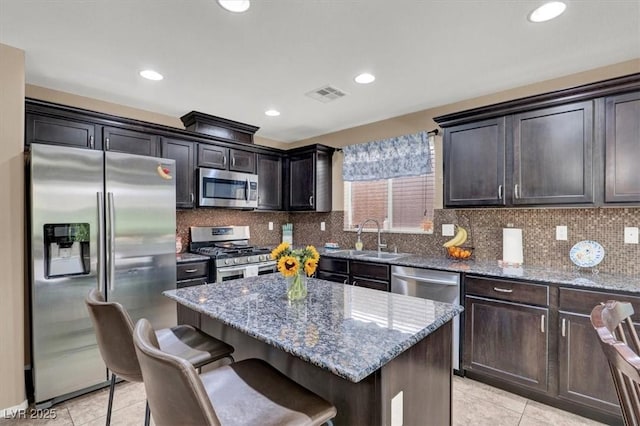 10230 Danskin Dr, Las Vegas, NV 89166 - kitchen with stainless steel appliances, light tile patterned floors, stone countertops, a center island, and decorative backsplash
