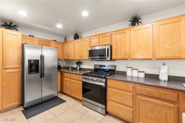 6488 Bentley Wood Ct, Las Vegas, NV 89130 - kitchen with appliances with stainless steel finishes, dark countertops, light tile patterned floors, recessed lighting, and light brown cabinetry