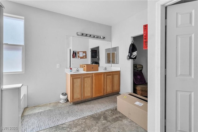 full bath with plenty of natural light, concrete flooring, and double vanity