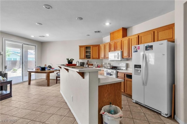 kitchen featuring white appliances, light tile patterned flooring, light countertops, brown cabinets, and recessed lighting