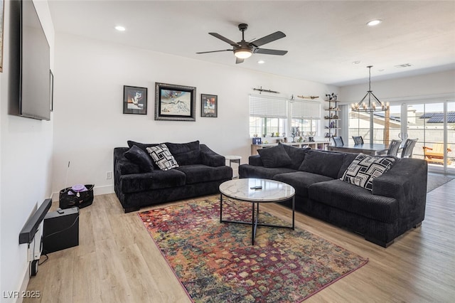 living area with ceiling fan, healthy amount of natural light, light wood-style floors, recessed lighting, and a chandelier