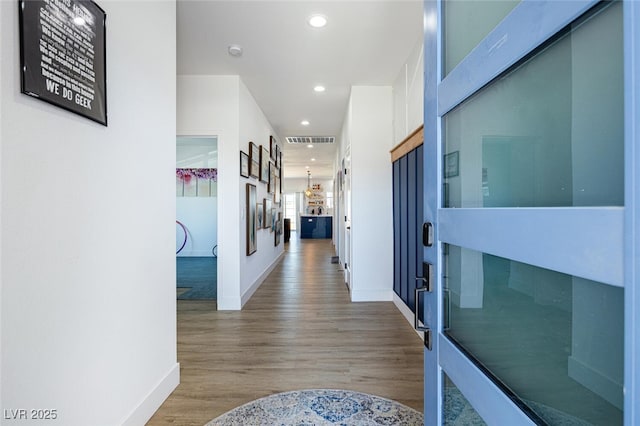 hall featuring baseboards, wood finished floors, and recessed lighting