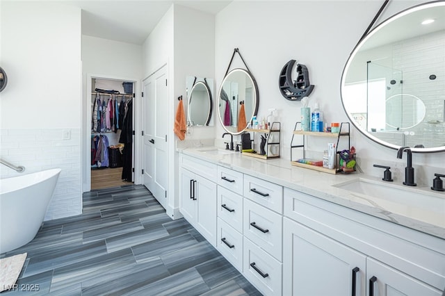 full bath featuring a shower stall, double vanity, tile walls, a freestanding tub, and a spacious closet