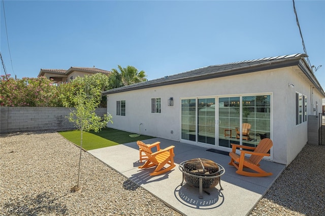 rear view of house featuring a fire pit, a patio, a fenced backyard, and stucco siding