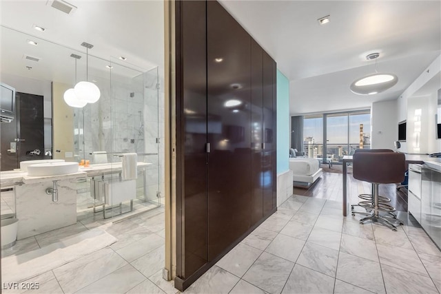 interior space with light marble finish flooring, modern cabinets, pendant lighting, and open floor plan