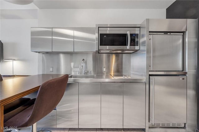 kitchen with stainless steel countertops, appliances with stainless steel finishes, modern cabinets, and a sink