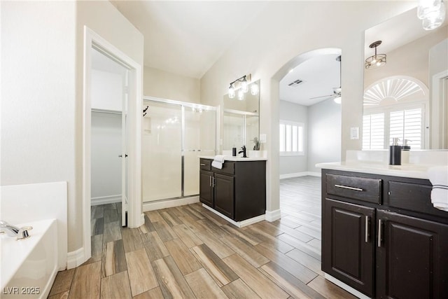 3882 Genoa Dr, Las Vegas, NV 89141 - bathroom featuring a stall shower, ceiling fan, wood finished floors, two vanities, and a garden tub