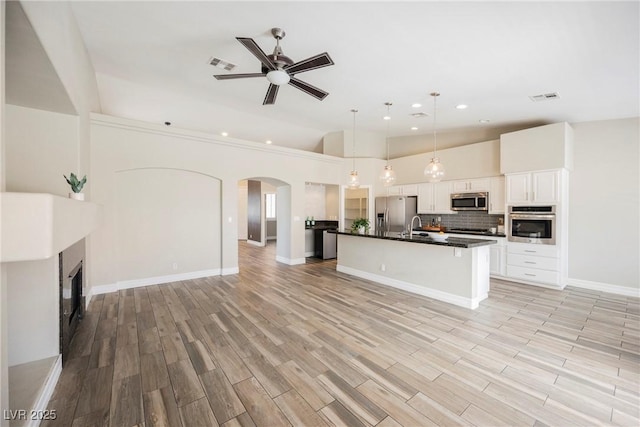 3882 Genoa Dr, Las Vegas, NV 89141 - kitchen with appliances with stainless steel finishes, open floor plan, dark countertops, arched walkways, and ceiling fan
