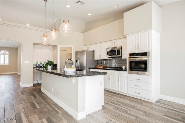 3882 Genoa Dr, Las Vegas, NV 89141 - kitchen featuring stainless steel appliances, arched walkways, a sink, light wood finished floors, and backsplash