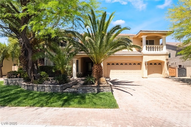 mediterranean / spanish house with stucco siding, decorative driveway, a balcony, a tile roof, and an attached garage