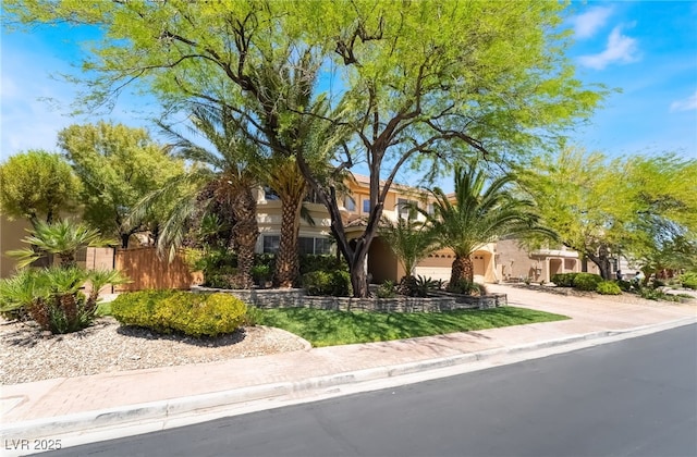 obstructed view of property featuring driveway, fence, stucco siding, and an attached garage