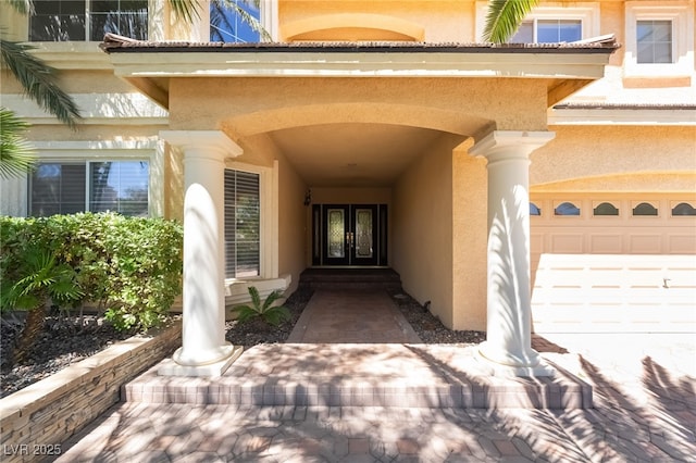 entrance to property featuring french doors, stucco siding, and a garage