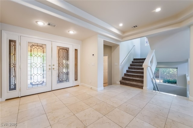 foyer entrance with french doors, stairway, a raised ceiling, and recessed lighting
