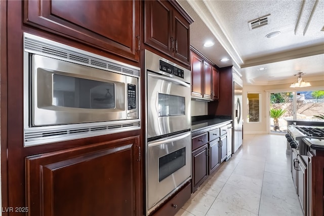 kitchen with stainless steel appliances, a chandelier, a textured ceiling, recessed lighting, and a tray ceiling