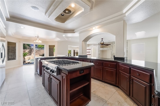 kitchen with stainless steel gas stovetop, a raised ceiling, ceiling fan, dark brown cabinets, and a textured ceiling