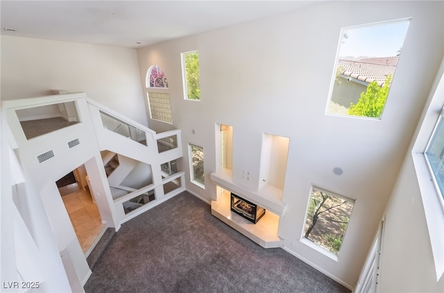 stairway featuring a towering ceiling and carpet floors
