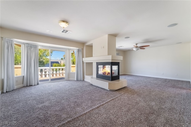 unfurnished living room with carpet flooring, a multi sided fireplace, ceiling fan, and baseboards