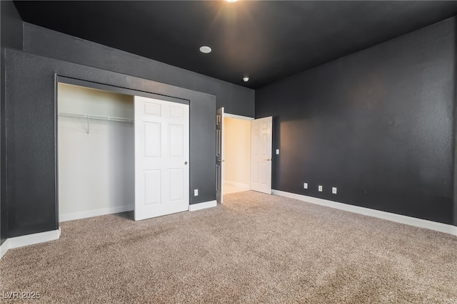 unfurnished bedroom featuring carpet floors, baseboards, and a closet