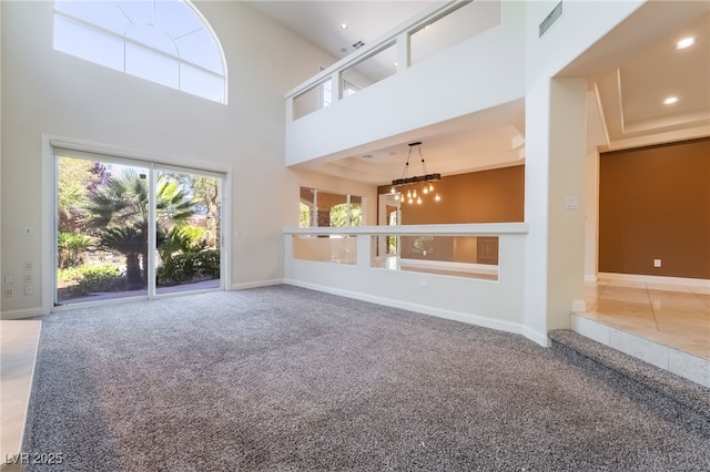 unfurnished living room with carpet flooring, a chandelier, a high ceiling, baseboards, and recessed lighting