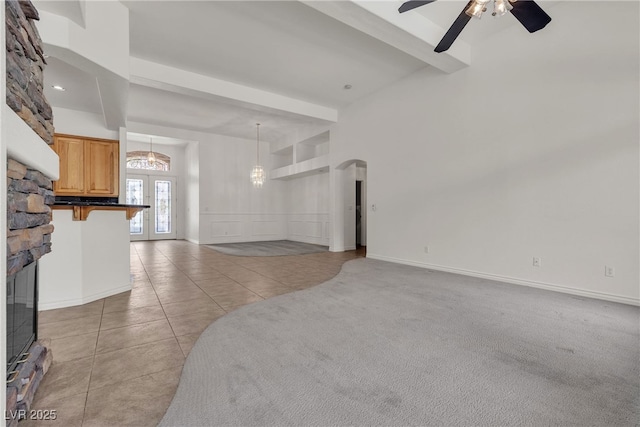 1532 Via Cassia, Henderson, NV 89052 - unfurnished living room featuring beamed ceiling, a chandelier, ceiling fan, light tile patterned floors, and a stone fireplace