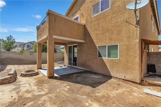 back of property featuring a fire pit, stucco siding, a patio, fence, and central air condition unit