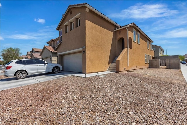 view of home's exterior with stucco siding, a garage, concrete driveway, and fence