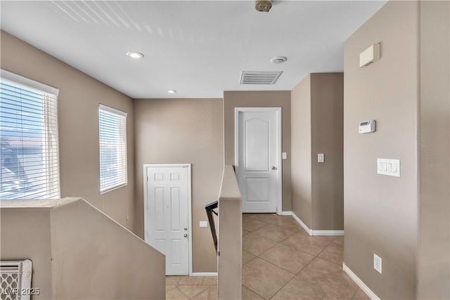 hall featuring baseboards, light tile patterned flooring, and recessed lighting