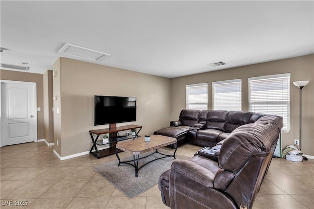 living room featuring light tile patterned floors, baseboards, and attic access