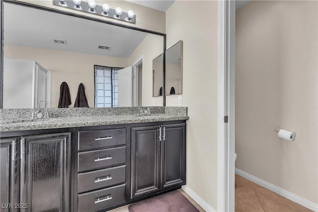 full bathroom with double vanity, baseboards, tile patterned flooring, and toilet