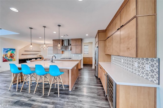 kitchen featuring stainless steel refrigerator, an island with sink, a kitchen breakfast bar, dark wood finished floors, and light countertops