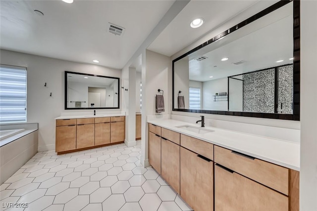 bathroom featuring recessed lighting, two vanities, tile patterned floors, and a bath