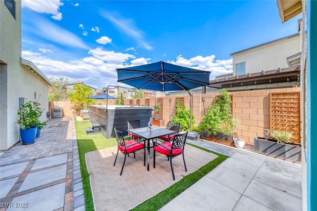 view of patio with a hot tub, a fenced backyard, and outdoor dining space