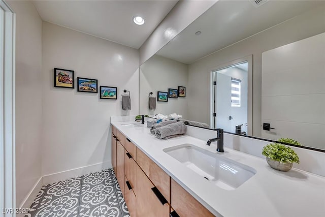 bathroom featuring baseboards, double vanity, and recessed lighting