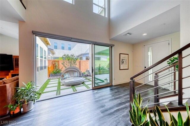 entryway with wood finished floors, stairway, a high ceiling, and baseboards