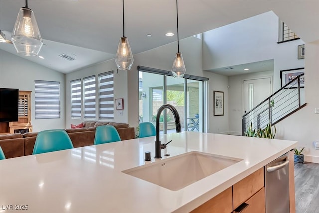 kitchen with open floor plan, a sink, lofted ceiling, light countertops, and wood finished floors