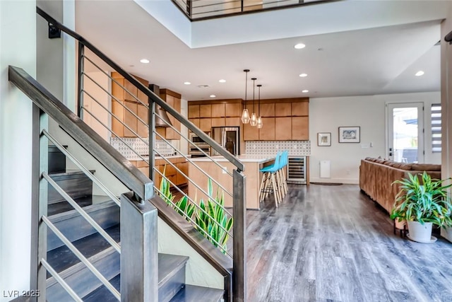stairway featuring wood finished floors, recessed lighting, wine cooler, a chandelier, and baseboards