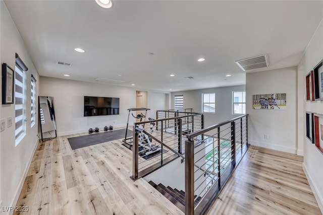 hallway with an upstairs landing, light wood-style floors, baseboards, and recessed lighting