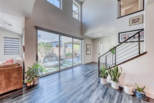 entrance foyer with plenty of natural light, wood finished floors, baseboards, a high ceiling, and stairway