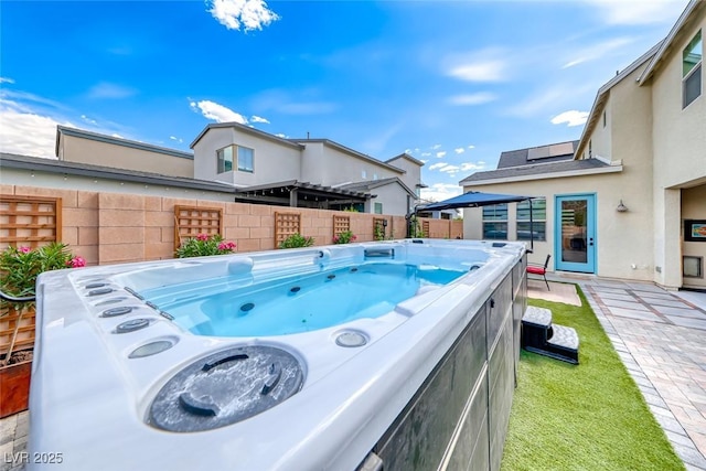 view of swimming pool featuring fence and a hot tub