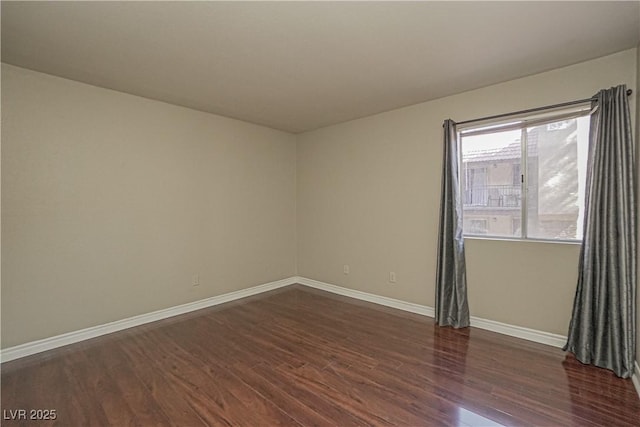 empty room featuring dark wood-style flooring and baseboards