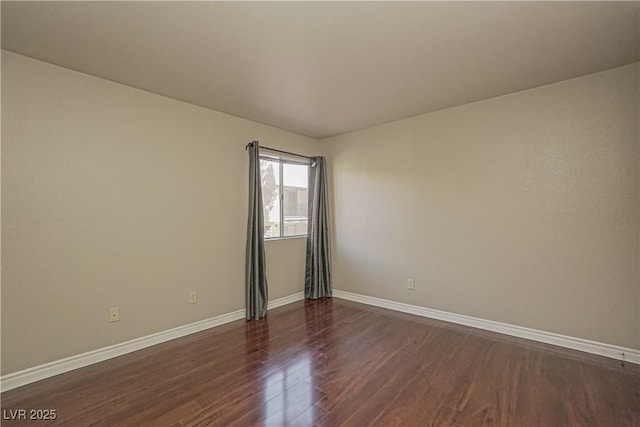 empty room featuring dark wood finished floors and baseboards