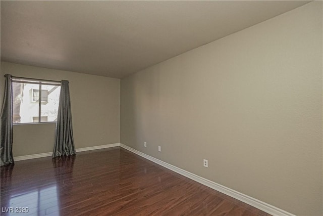 spare room featuring dark wood-type flooring and baseboards
