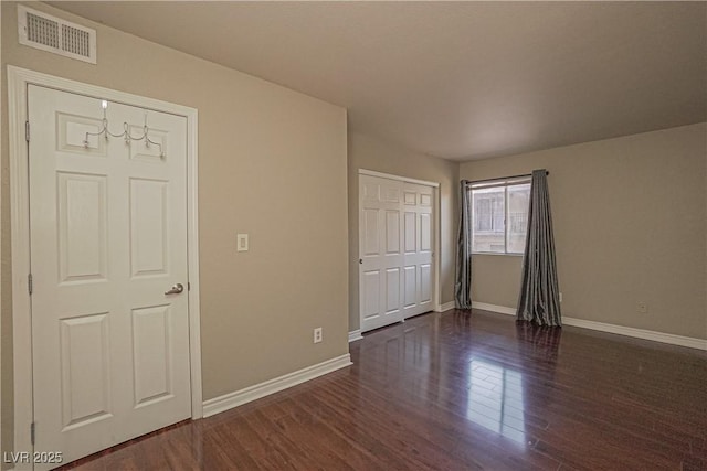 unfurnished bedroom featuring dark wood-style floors, baseboards, and a closet