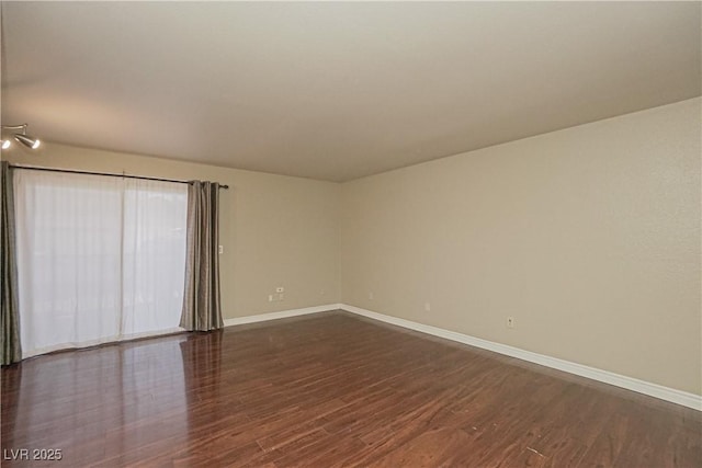 unfurnished room with baseboards and dark wood-style floors