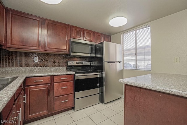 kitchen featuring appliances with stainless steel finishes, light tile patterned floors, and backsplash