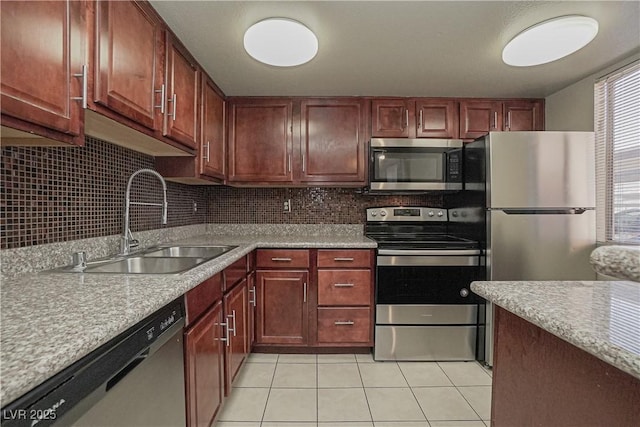 kitchen featuring appliances with stainless steel finishes, a sink, light tile patterned floors, tasteful backsplash, and light countertops