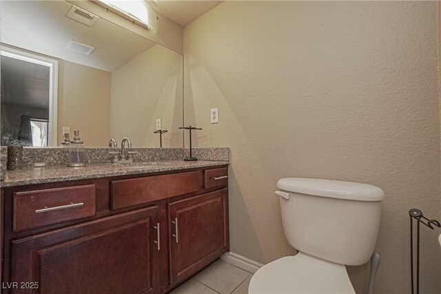 half bathroom featuring tile patterned floors, toilet, and vanity