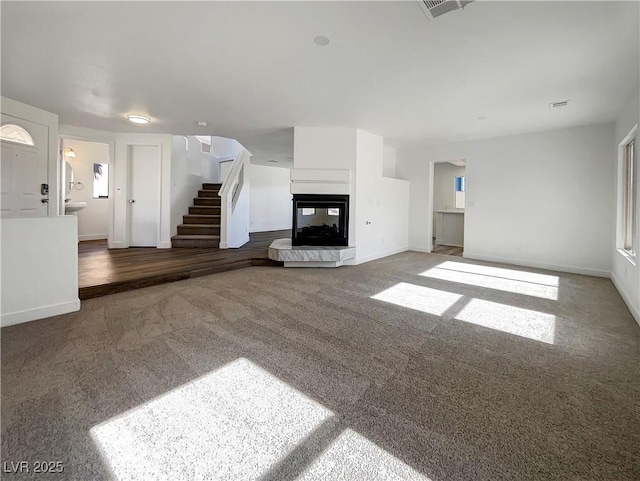 983 Plantain Lily Ave, Las Vegas, NV 89183 - unfurnished living room featuring stairs, a multi sided fireplace, carpet, and baseboards